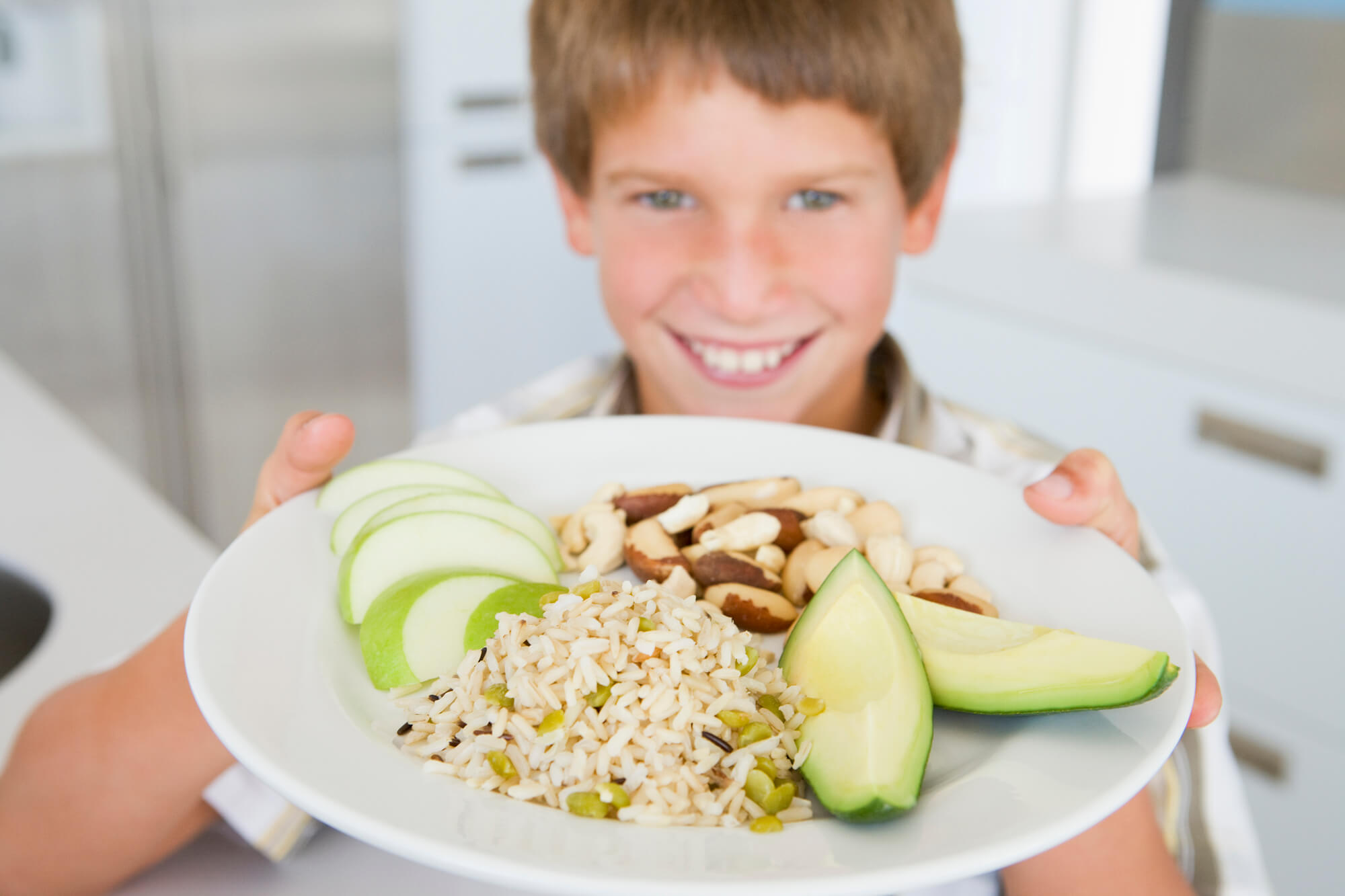 a child holding a plateful of tooth-friendly foods as recommended by a pediatric dentist in 33146 